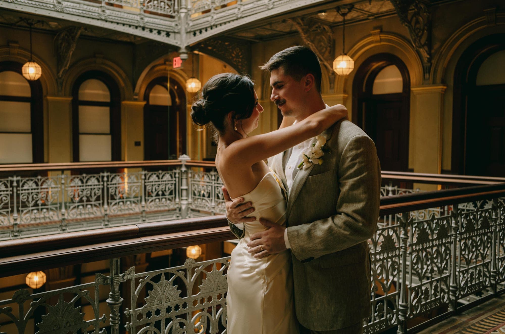 Andie & Jake embracing on the balcony of The Beekman atrium